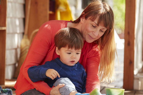 Educator helping child to put on shoes 