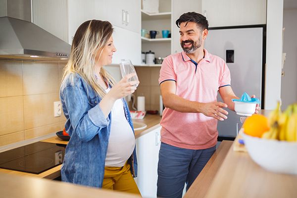 Man and woman drinking and making juice in kitchen