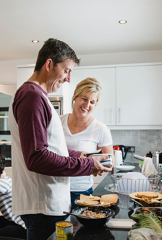 Couple preparing food with children inthe background