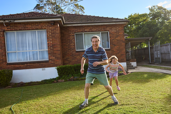 Man playing with child outside home