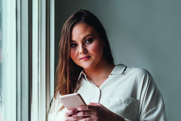 Serious woman thinking and using mobile phone indoors