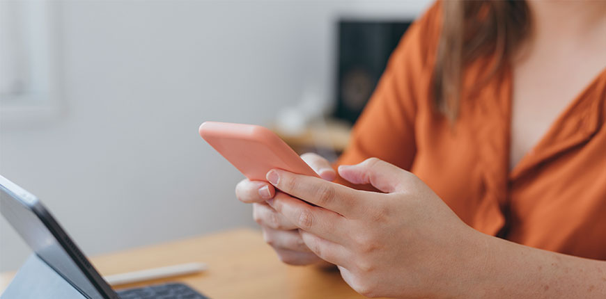 Female wearing orange top using mobile phone and tablet 