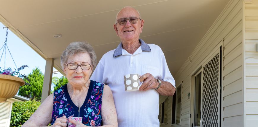 Senior couple at home holding coffee cups
